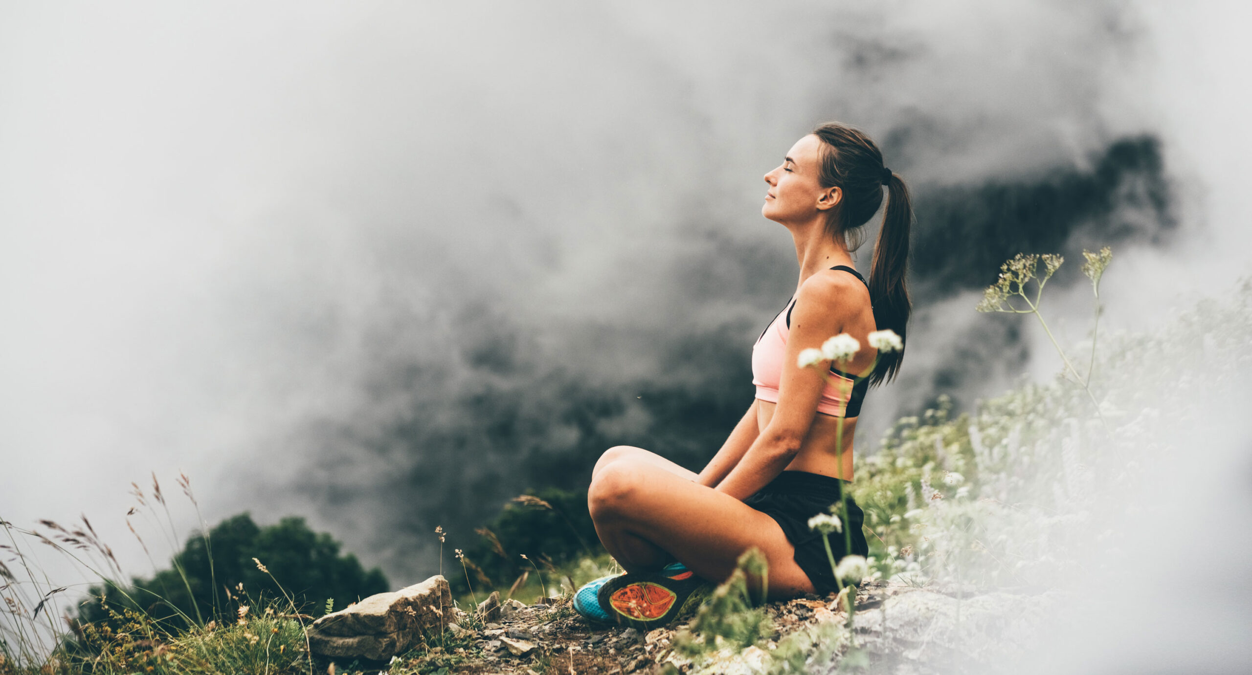 Frau meditiert in den Bergen im Nebel. Gesund Leben: mehr Energie, Wohlbefinden und Spaß im Leben